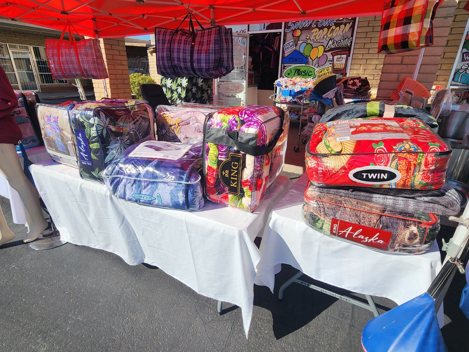 a table with a bunch of bedding on it and a tent in the background .