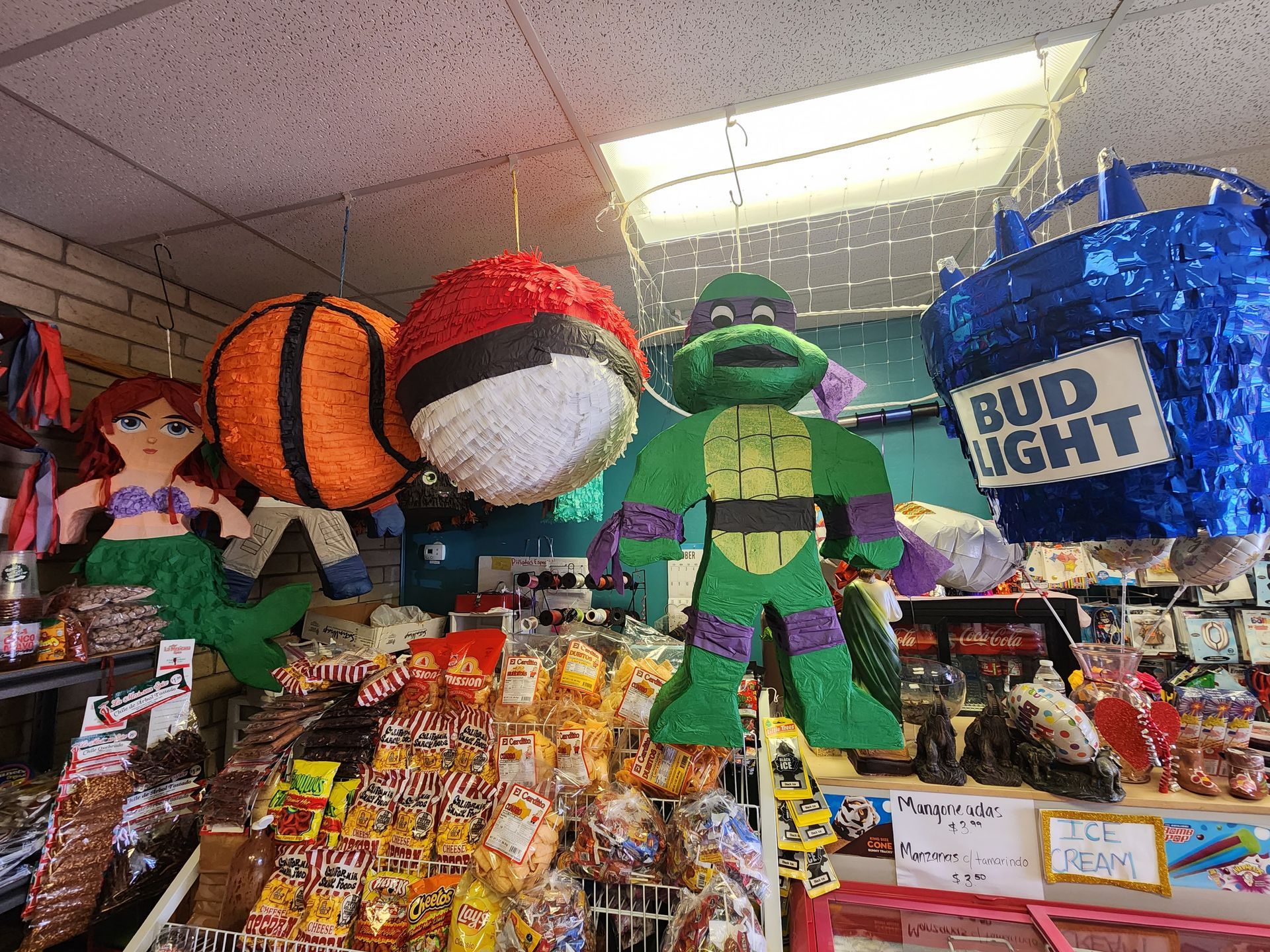 a store filled with lots of pinatas including a turtle and a basketball .