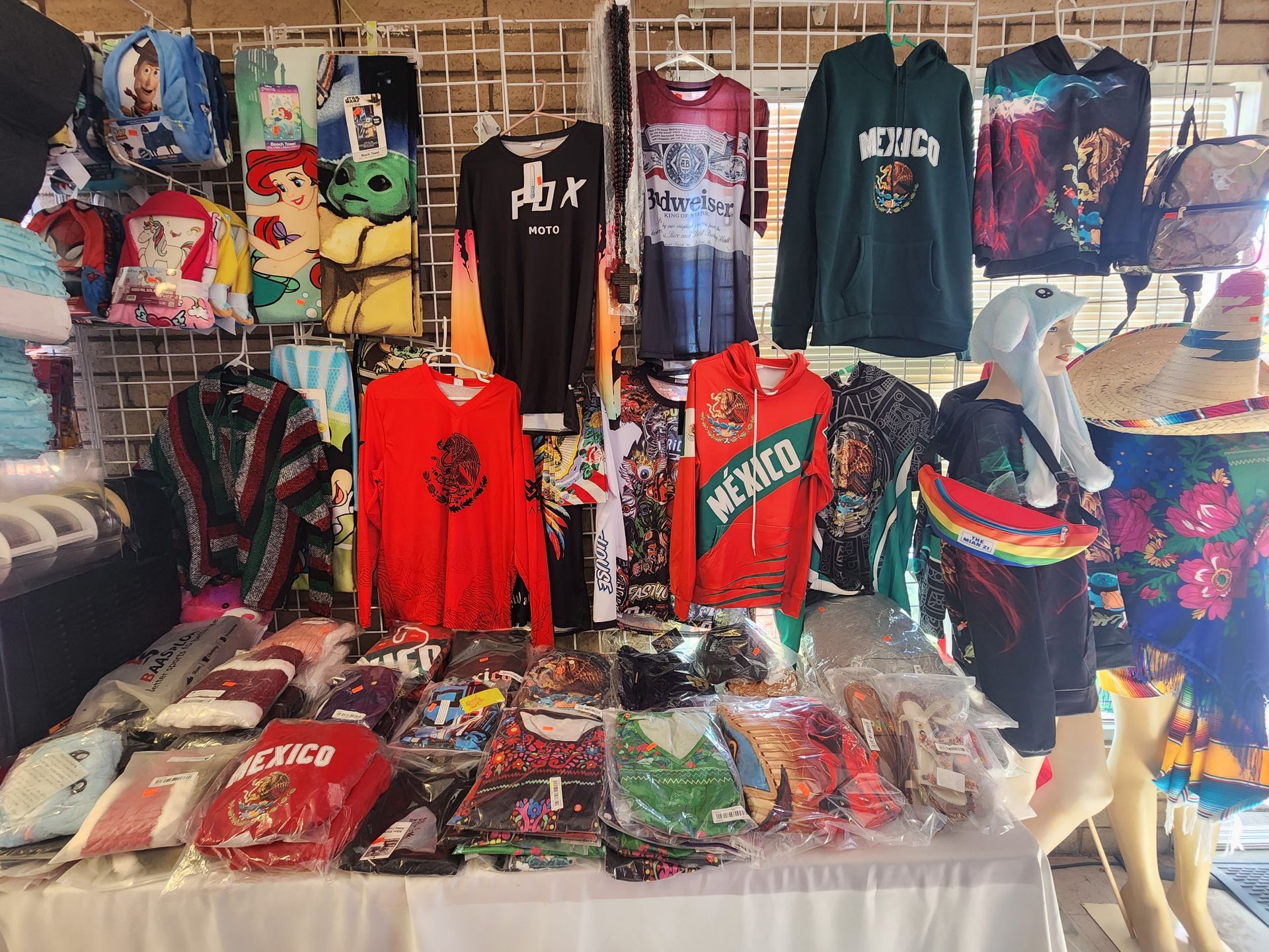 a table filled with lots of shirts and hats .