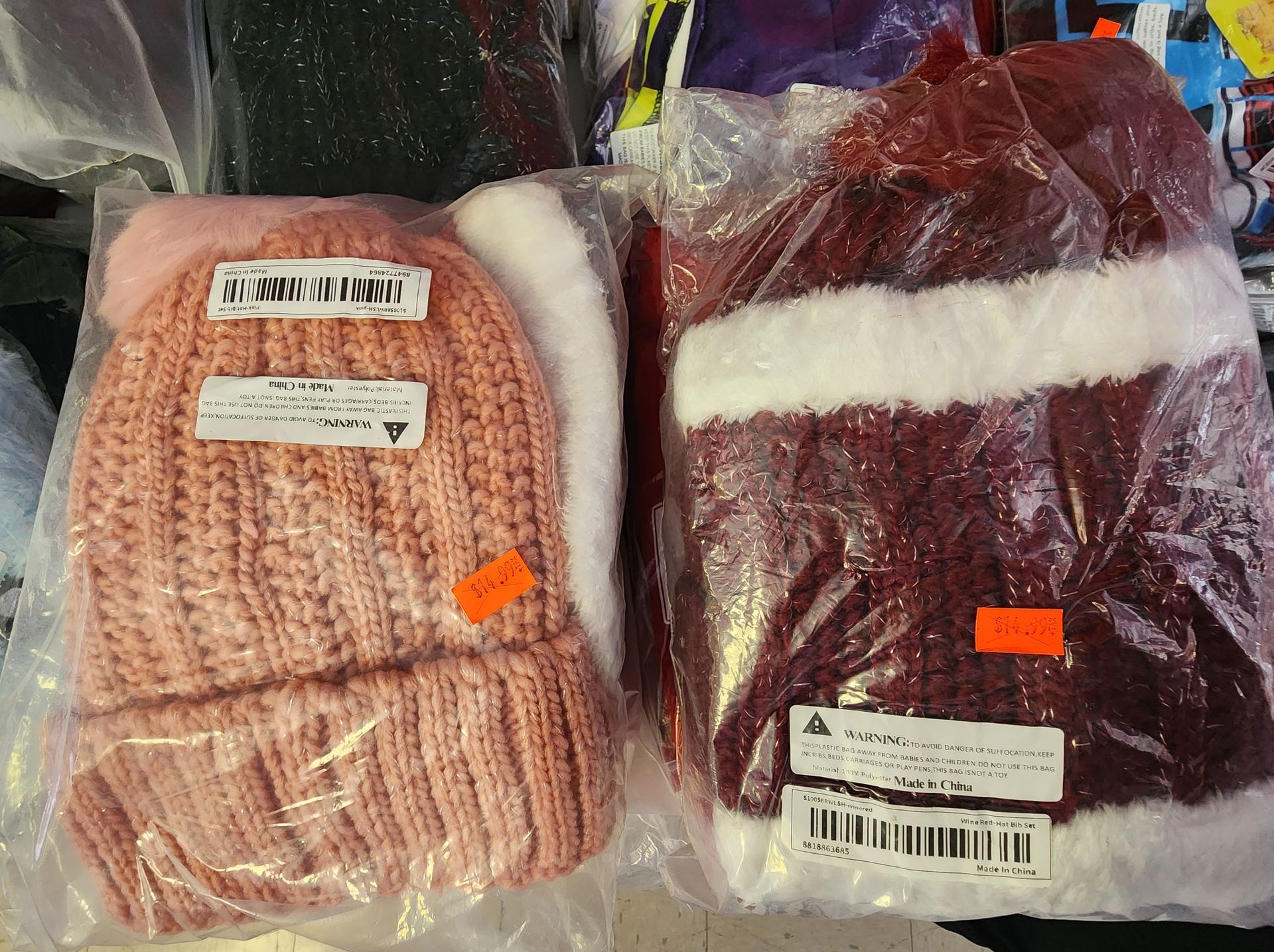 a pink hat and a red hat are in plastic bags