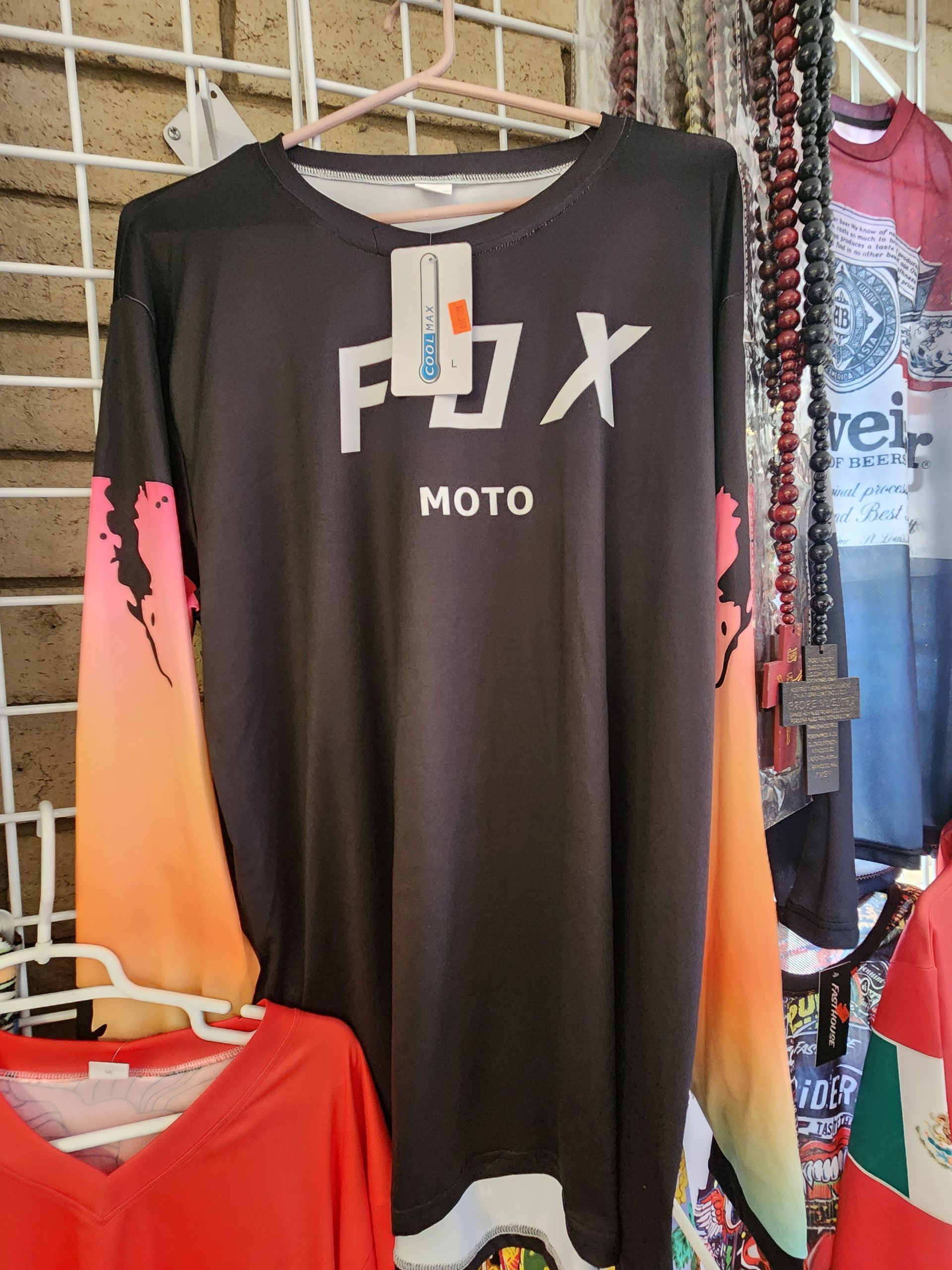 a black and orange fox moto jersey is hanging on a rack .