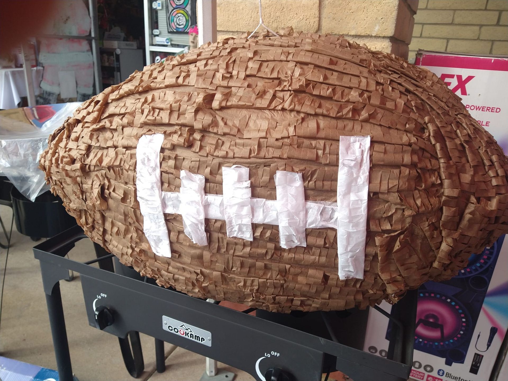 a piñata in the shape of a football is sitting on a grill .