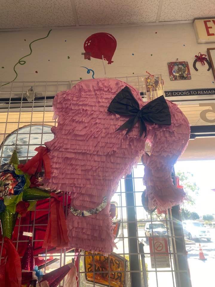 a pink piñata with a black bow is hanging in a store .