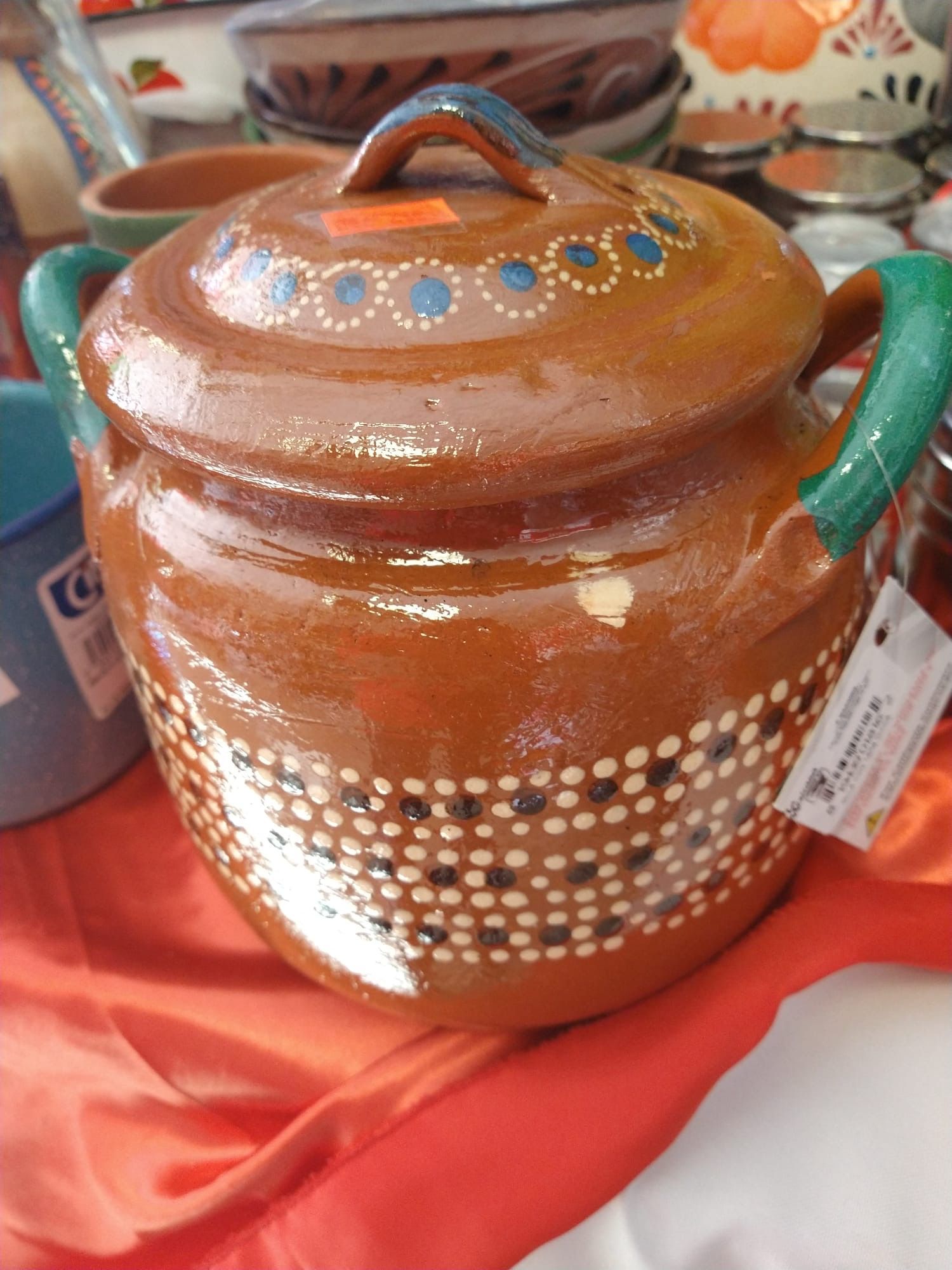 a brown pot with green handles and a lid is sitting on a table .