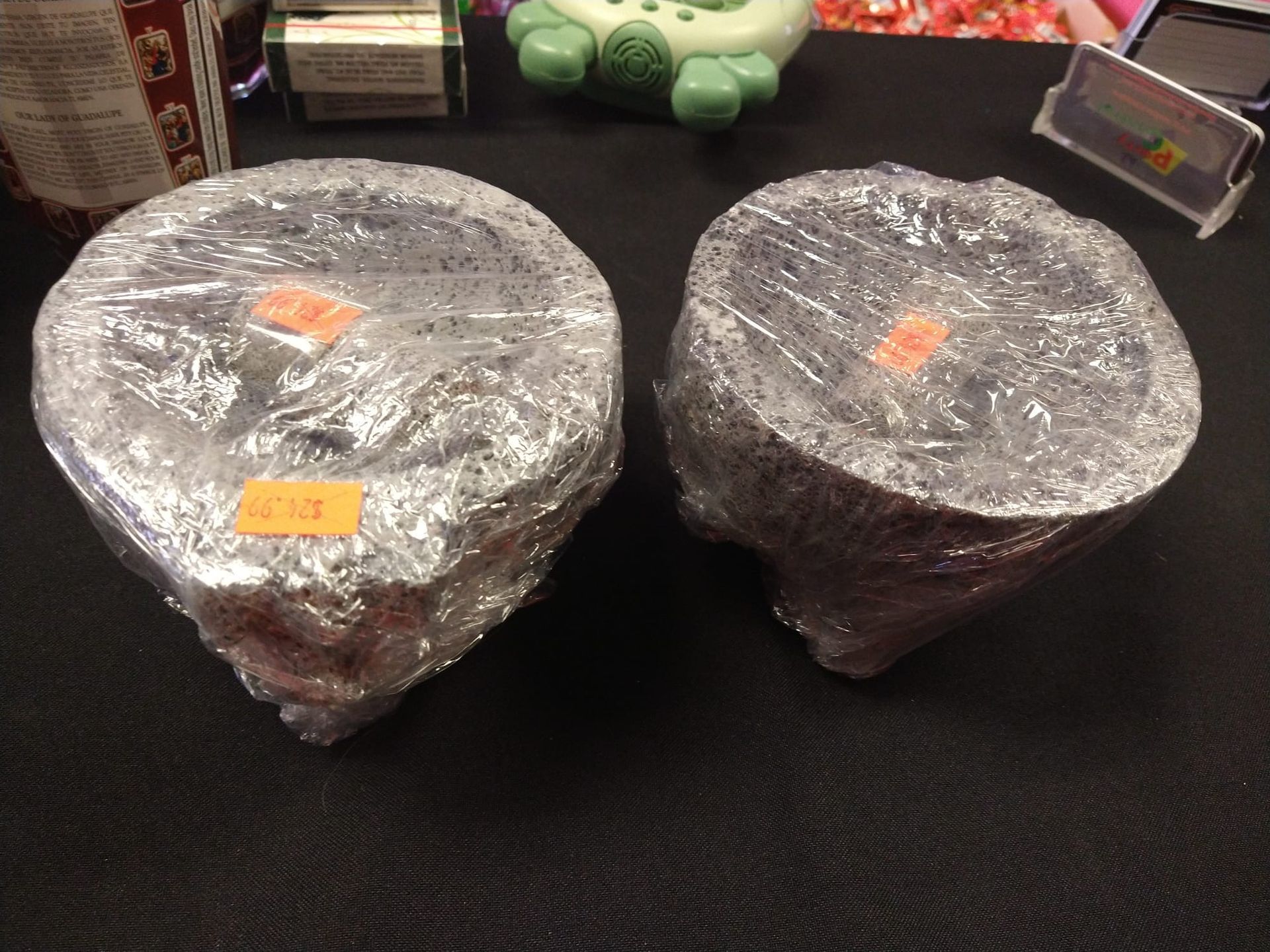 two stone mortar and pestles wrapped in plastic on a table