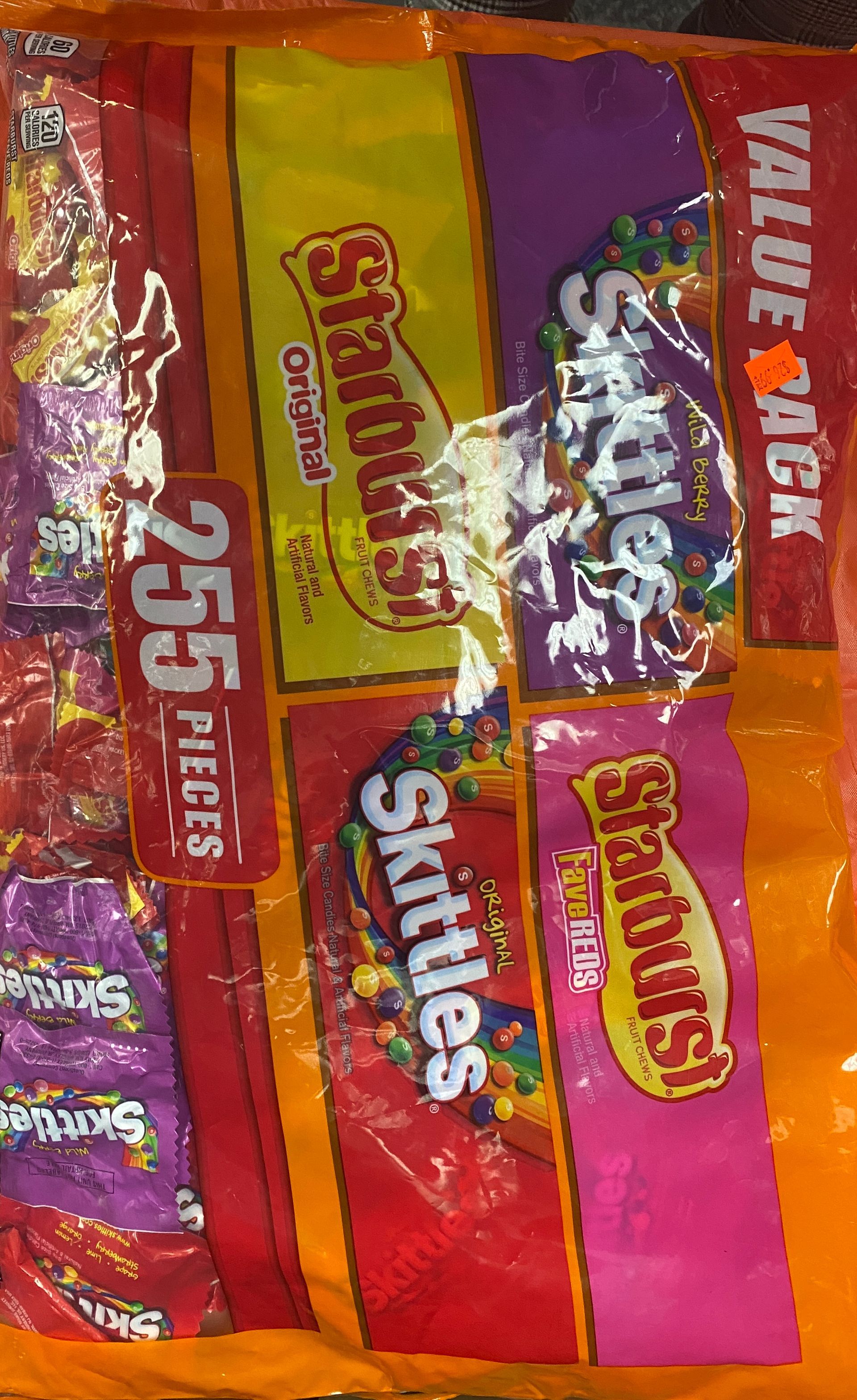 a candy mix bag of skittles and starburst is sitting on a table .