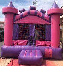 a pink and purple bouncy house is sitting on the ground 