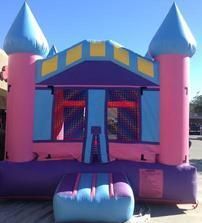 a pink and blue bouncy castle is sitting in a parking lot 