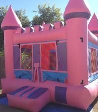 a pink bouncy castle is sitting on top of a blue tarp 