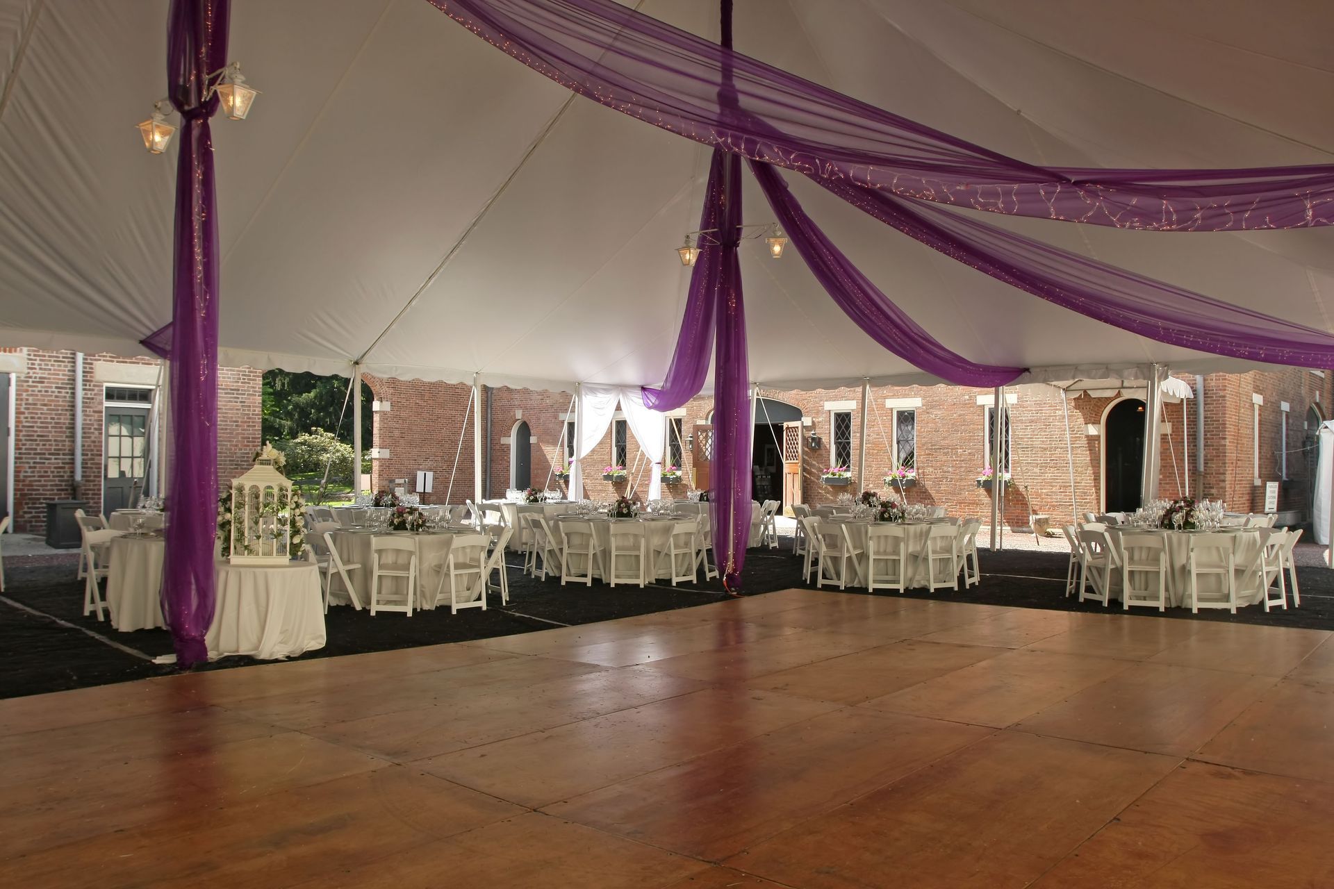 an empty dance floor under a tent with tables and chairs