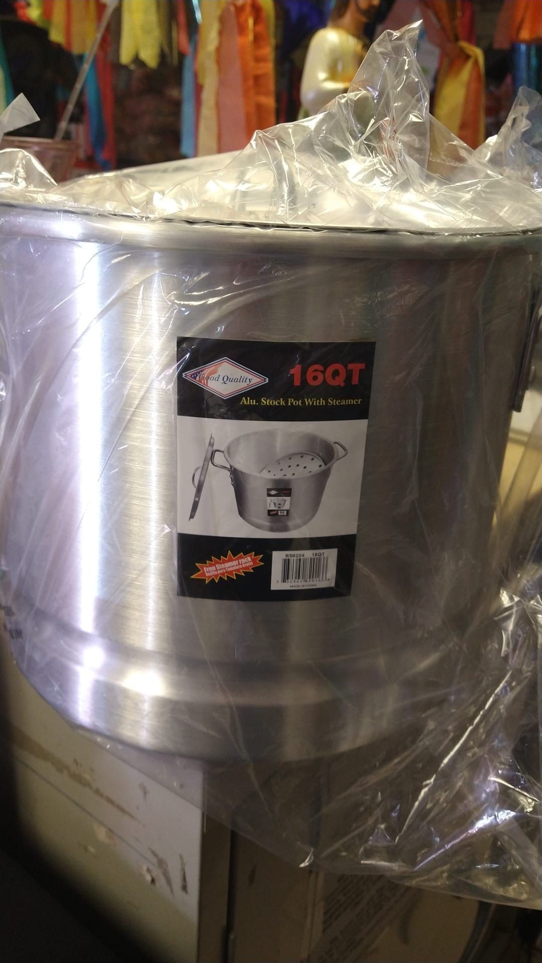 a large aluminum pot with a label on it is wrapped in plastic .