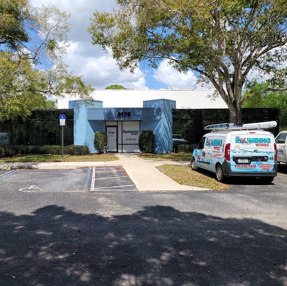 A plumbing company van is parked in front of a building