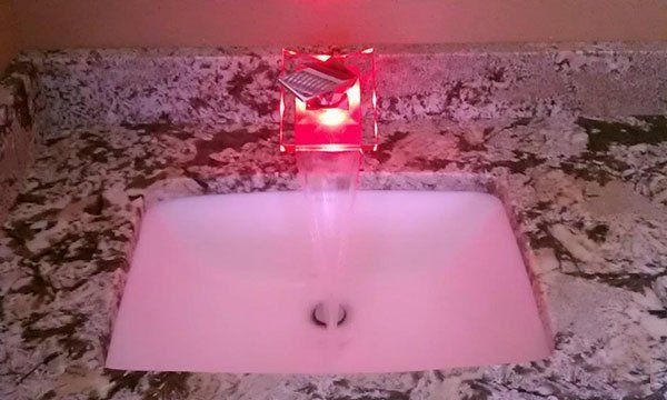 A bathroom sink with a red light on the faucet.