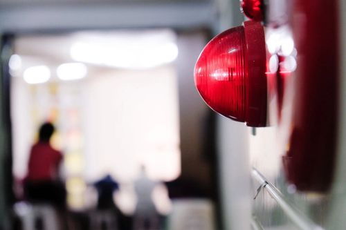 Red alarm light on a wall with blurred people in the background