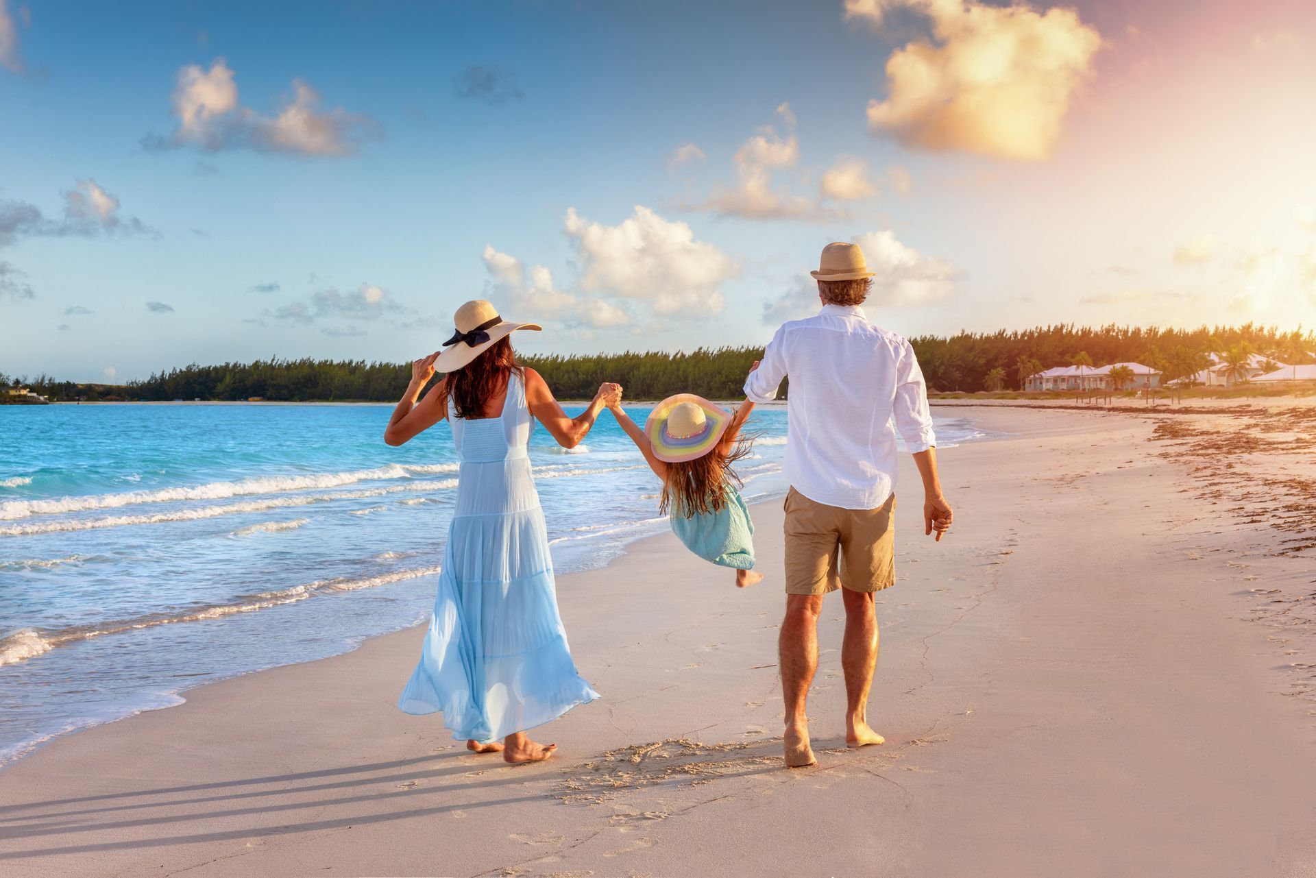Two people walking hand in hand on a sunny beach at sunset