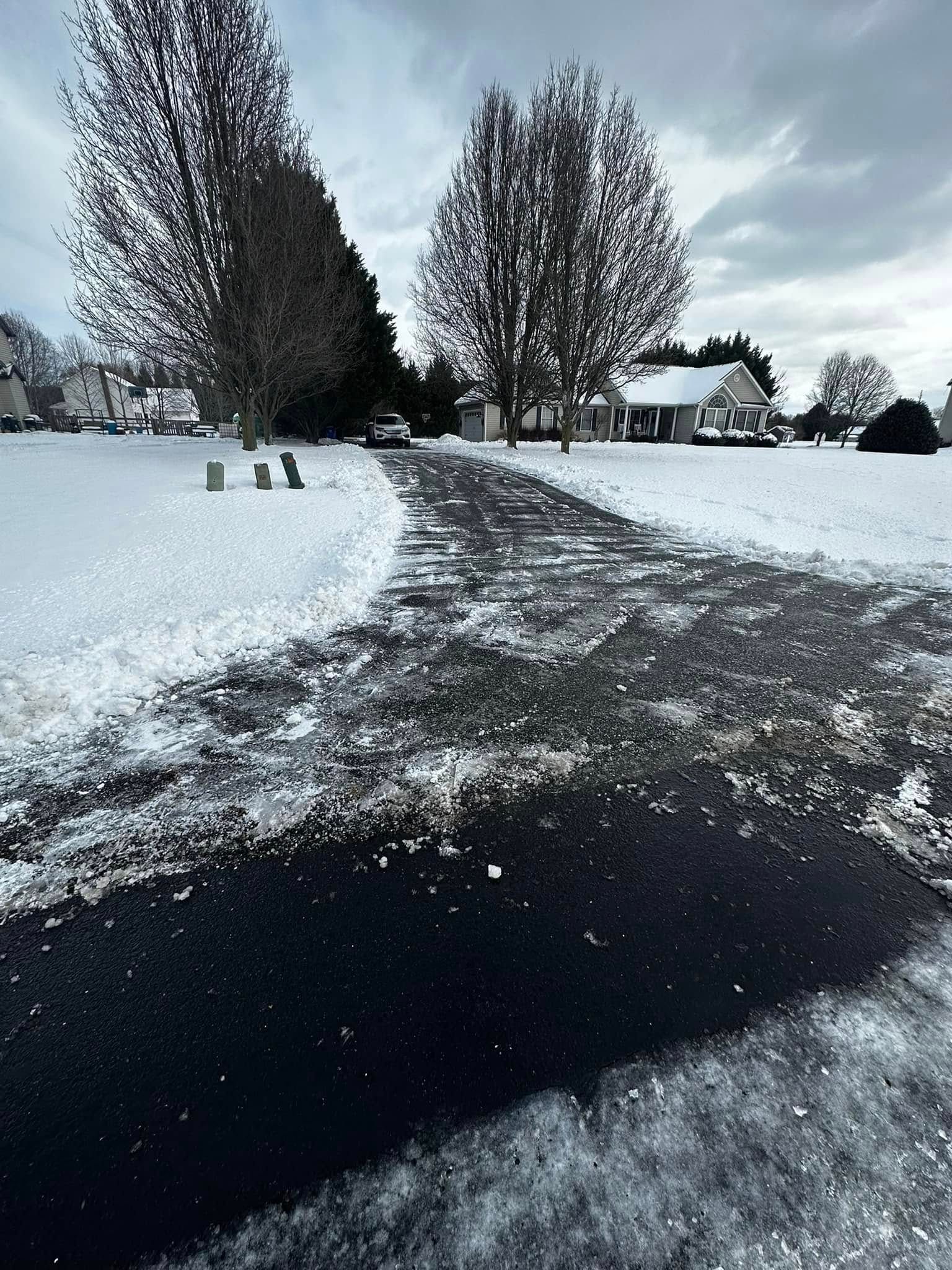 A photo of a snowy driveway leading to a house.