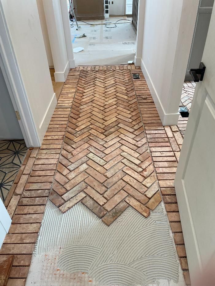 A hallway with a herringbone pattern of bricks on the floor.