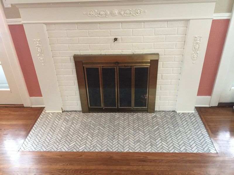 A fireplace with a herringbone tile floor in a living room.