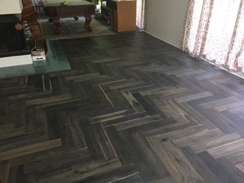 A living room with a herringbone wooden floor and a pool table.