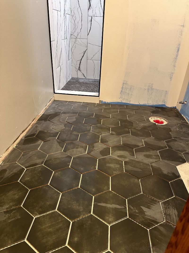 A bathroom with a hexagonal tile floor and a shower.