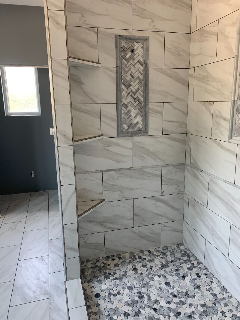 A bathroom with a walk in shower and a window.