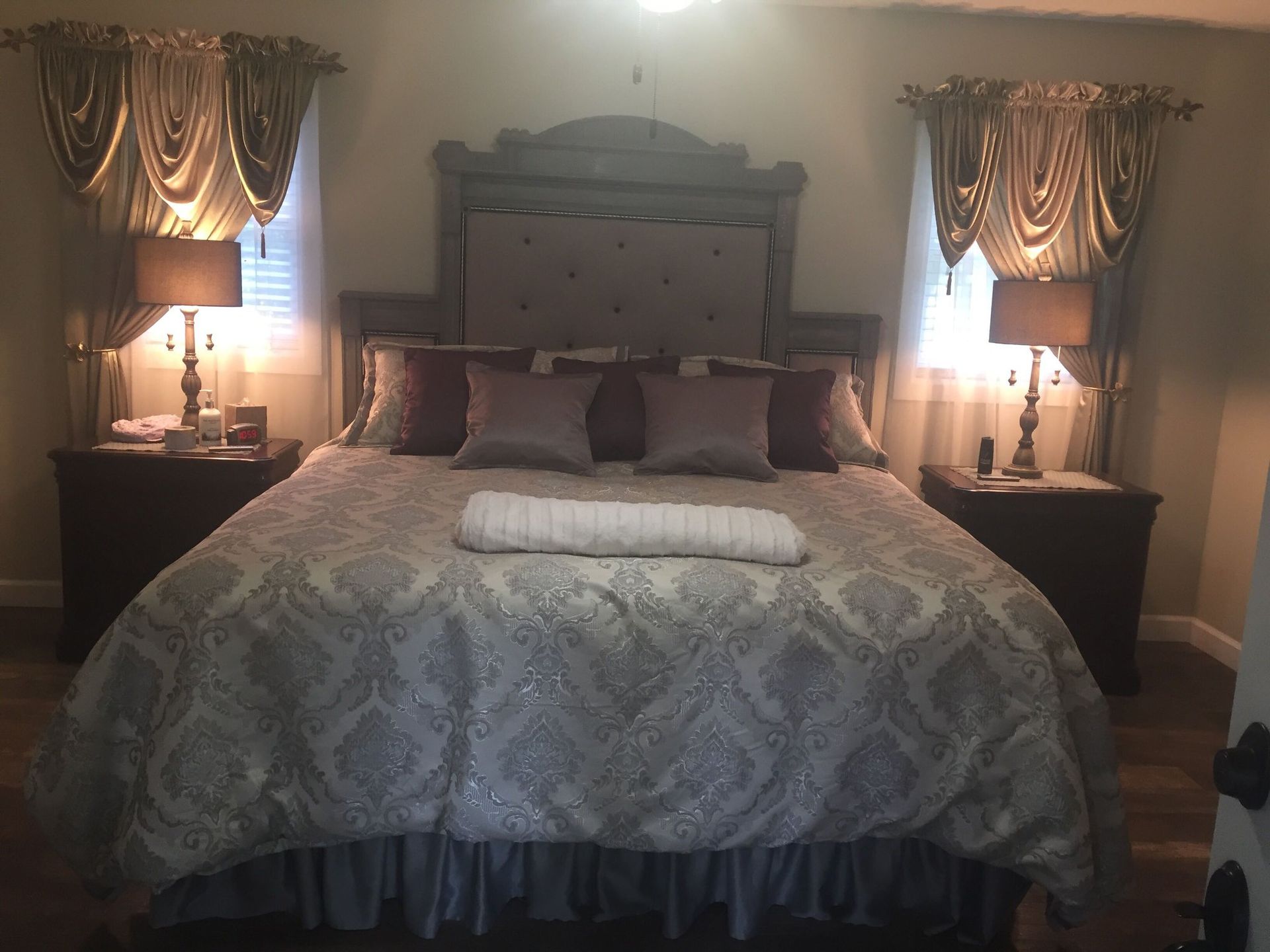 Bedroom with a large bed, nightstands, lamps, and decorative curtains.