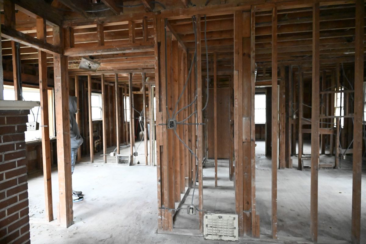 Interior of a house gutted to the studs during renovation. Exposed wooden frames and brick fireplace.