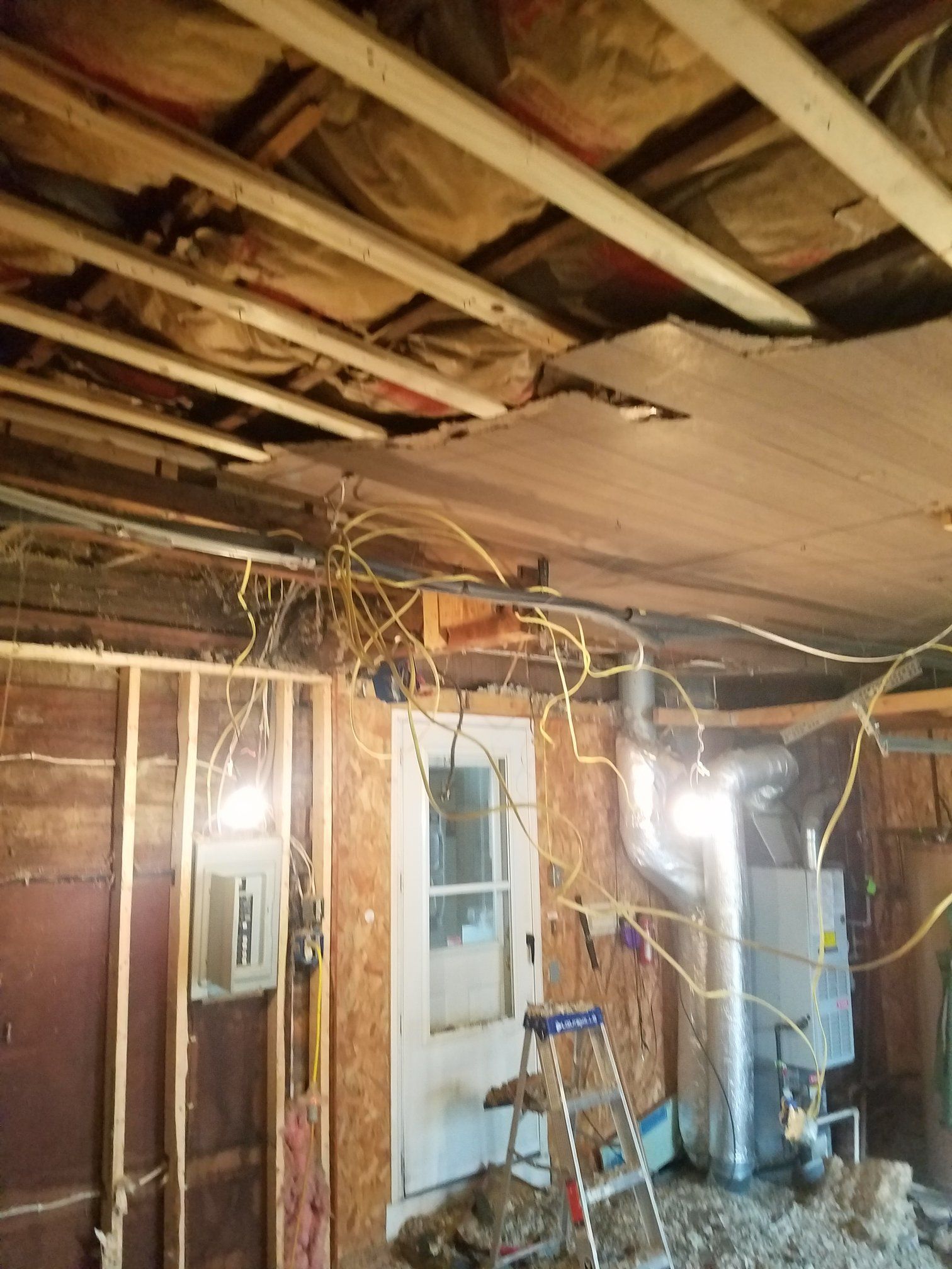 Interior view of a room under construction with exposed wiring, insulation, and an HVAC unit.