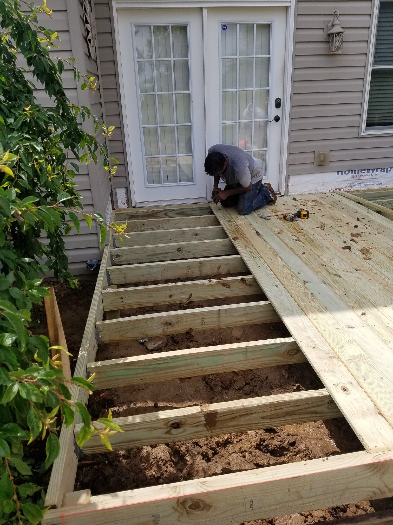 Person installing deck boards on a wood frame staircase leading to a doorway.