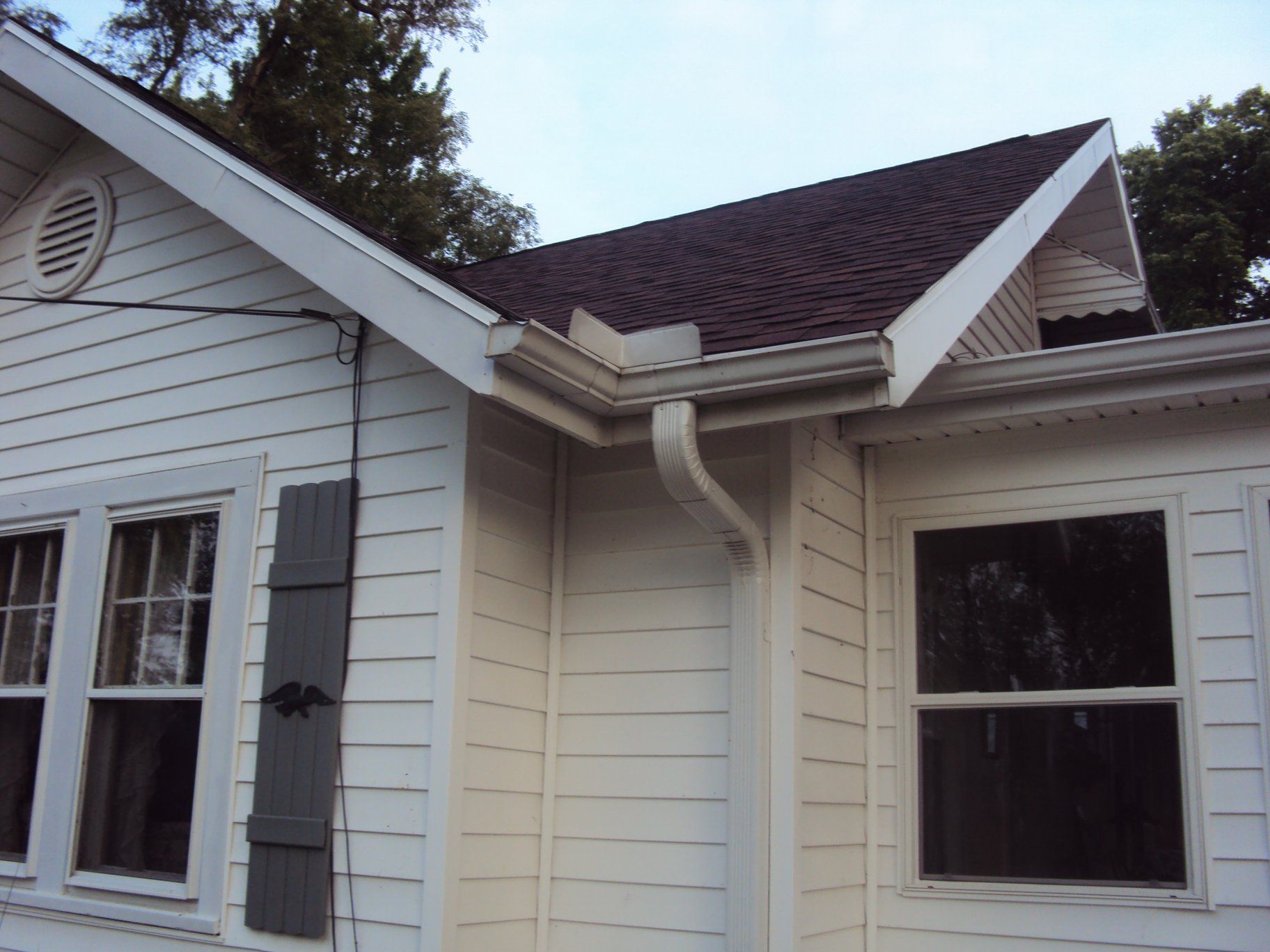 White house exterior with dark brown roof, windows, and gutter system.