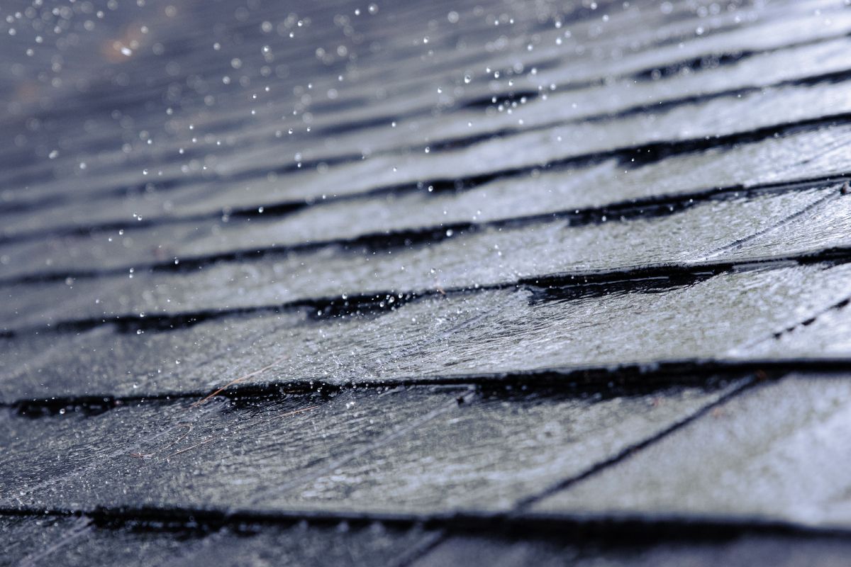 Rain falling on a dark, tiled roof; close-up view.