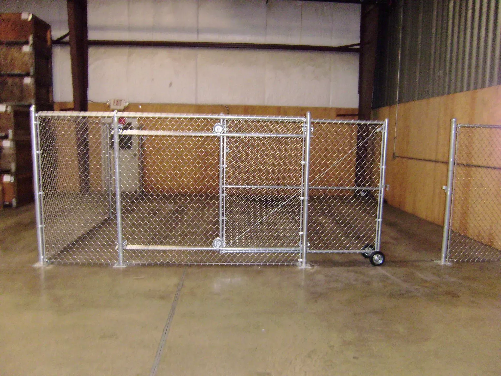 Chain-link gate enclosure on a concrete floor inside a warehouse.