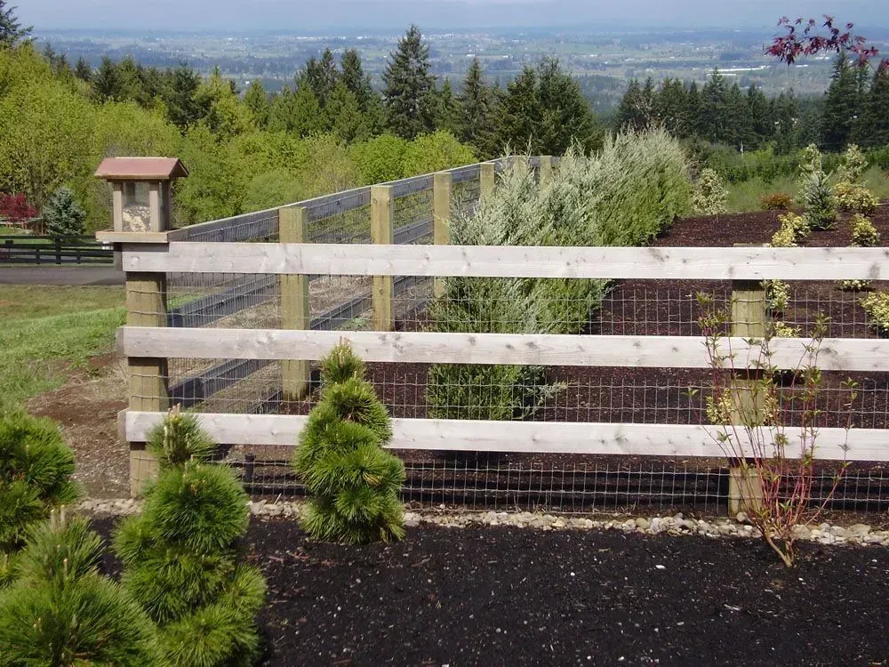 Wooden fence and shrubs overlooking a valley and distant cityscape