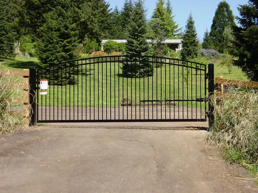 Black metal driveway gate at the entrance to a landscaped garden property