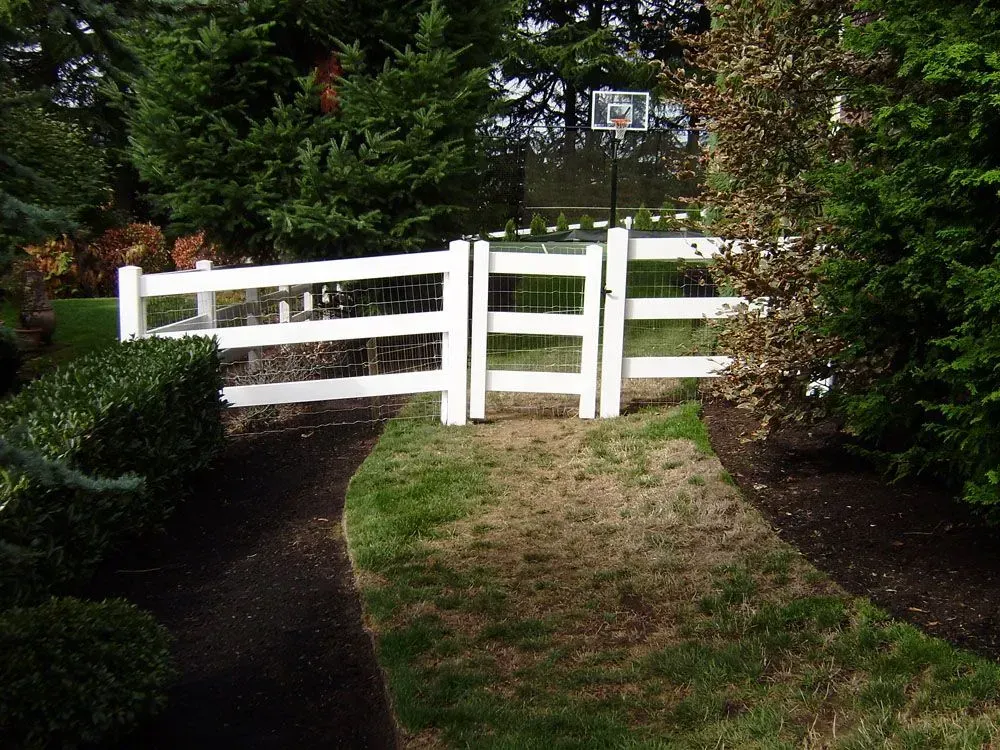 White wooden fence blocking a garden path, surrounded by green shrubs and trees