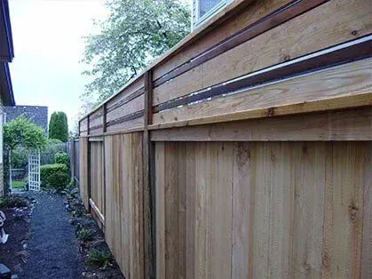 Wooden privacy fence along a narrow side yard beside a house and walkway