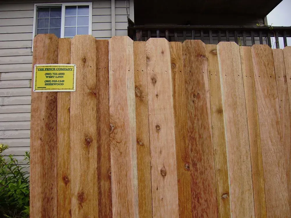 Wooden fence with a yellow warning sign in front of a house window