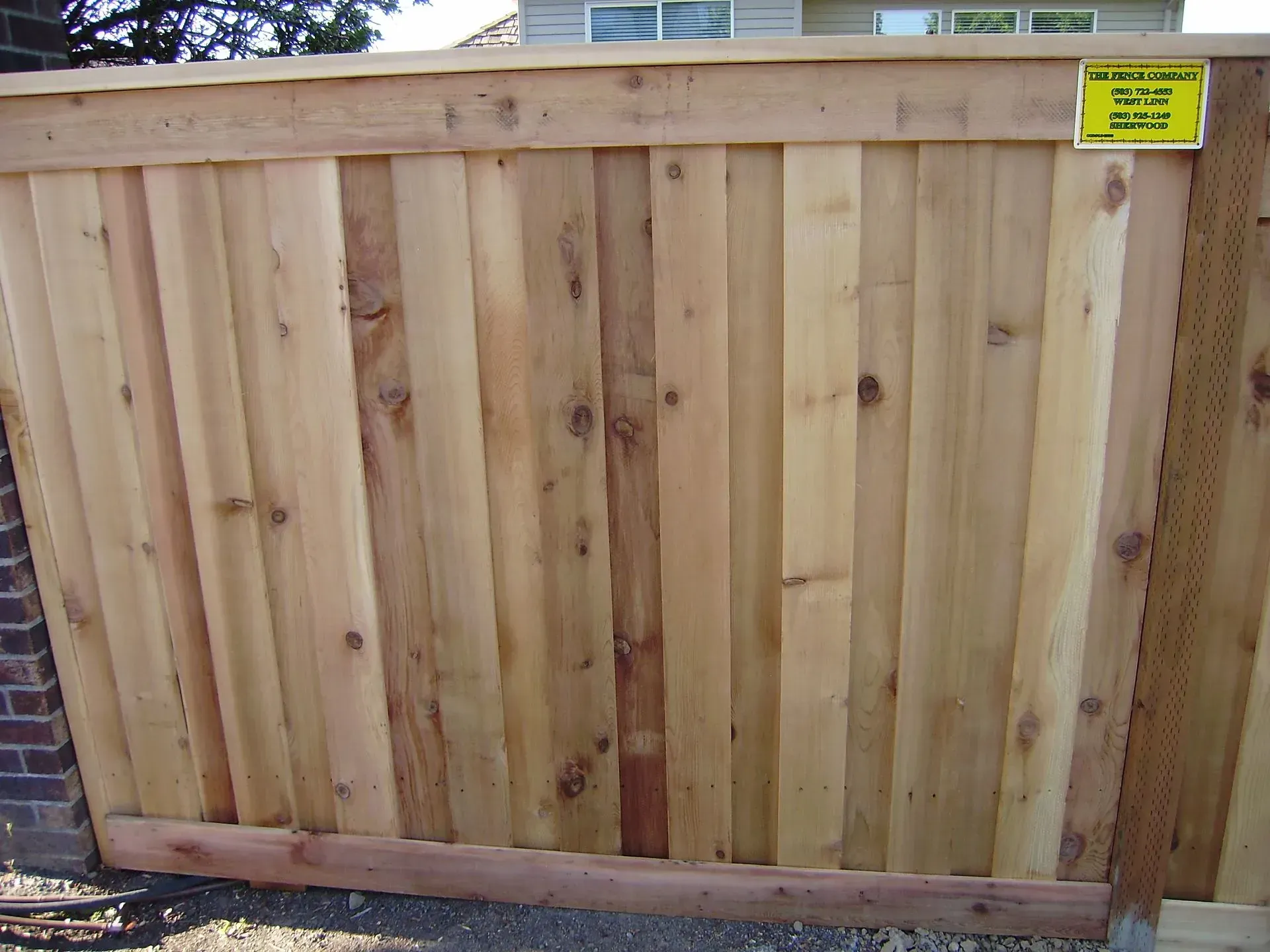 Wooden privacy fence with a yellow warning sign at the top right.