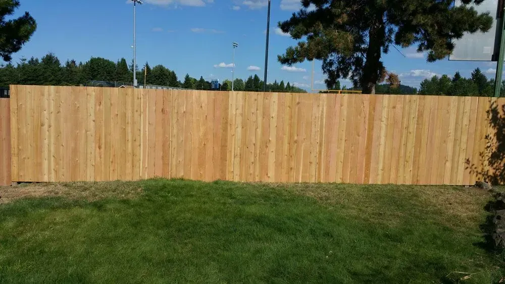 Wooden privacy fence behind a grassy yard under a clear blue sky