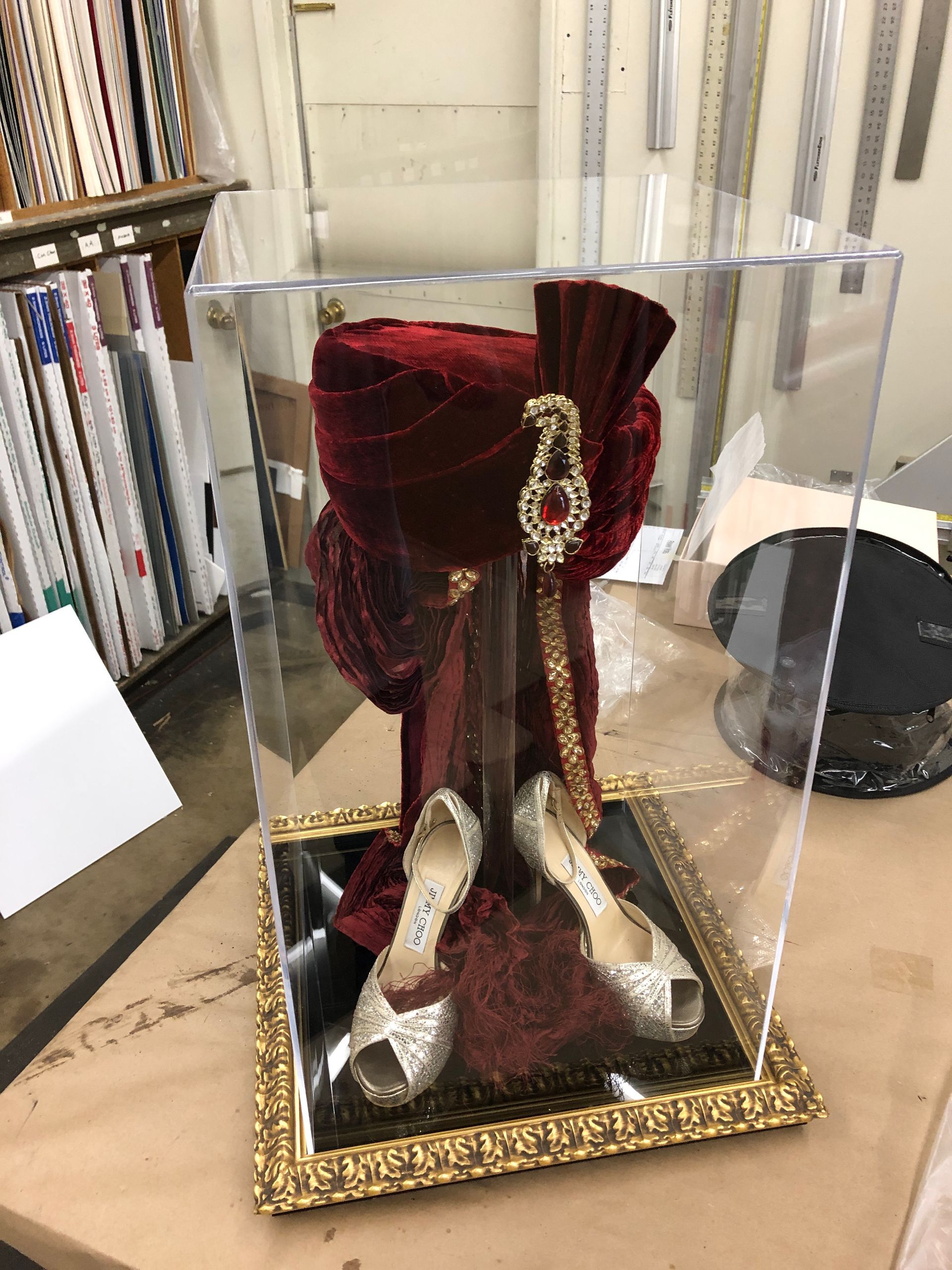 A hat and shoes are in a clear box on a table.