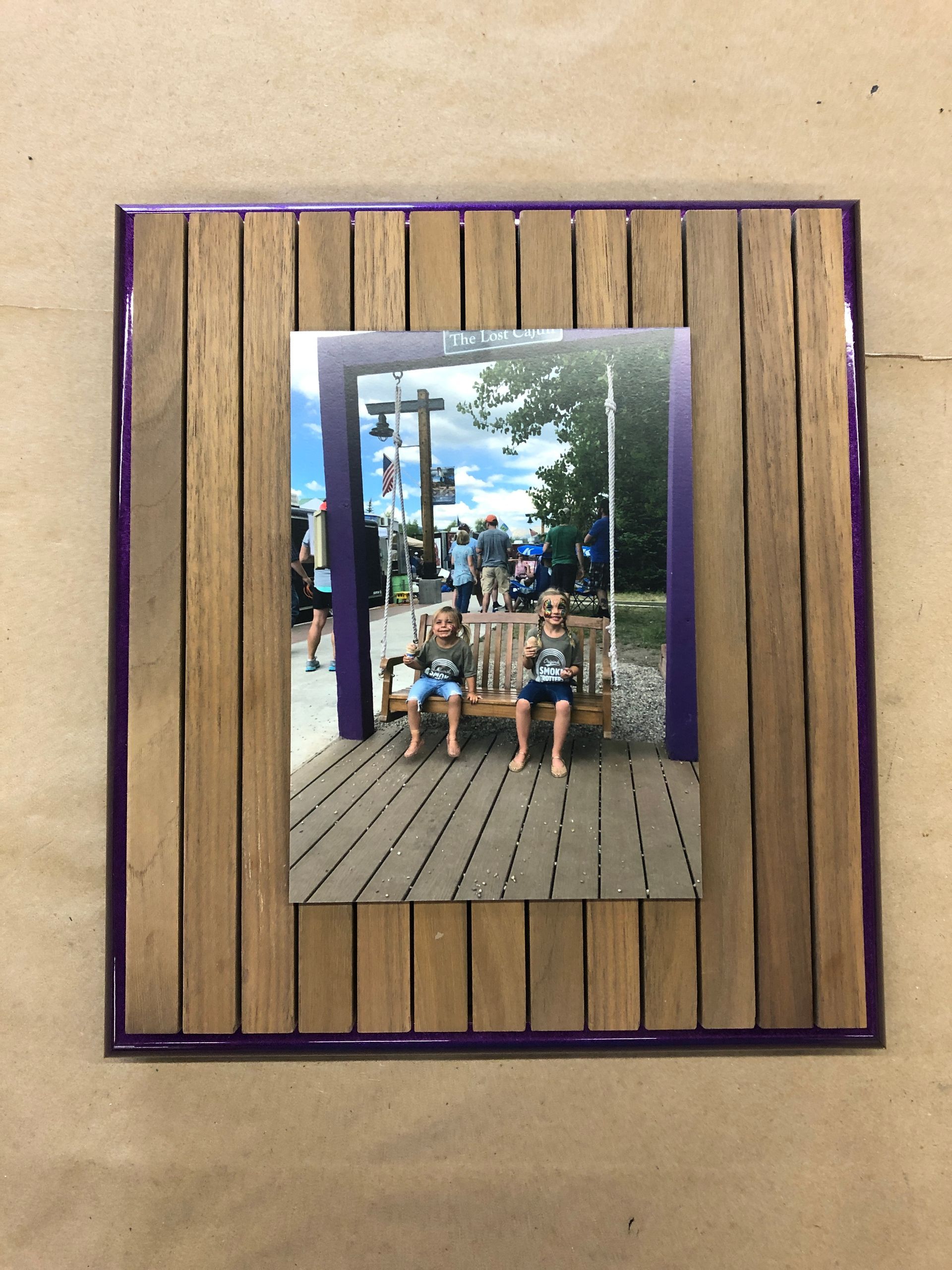 A picture of two children sitting on a bench in a wooden frame