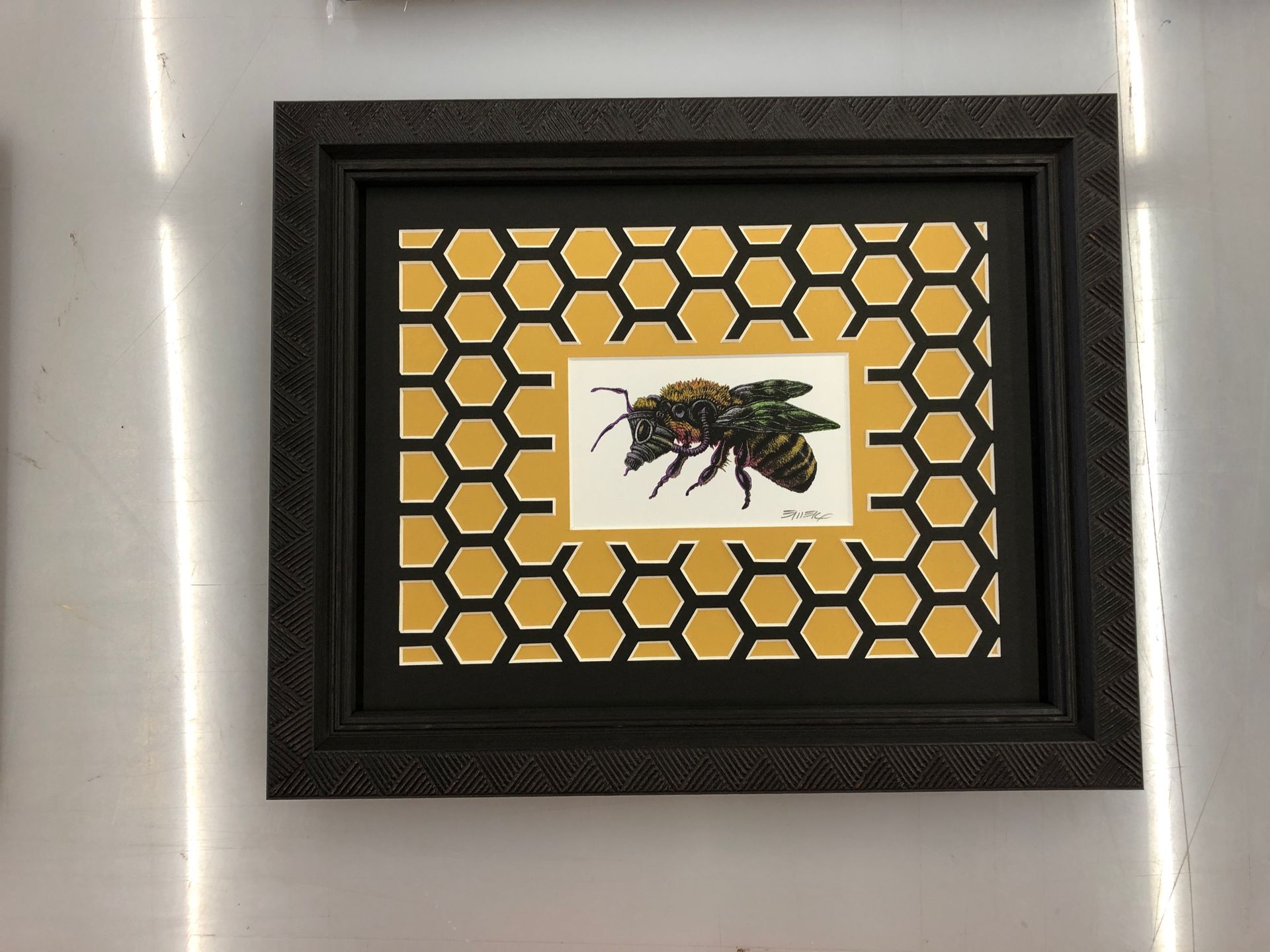 A picture of a bee in a frame on a wall