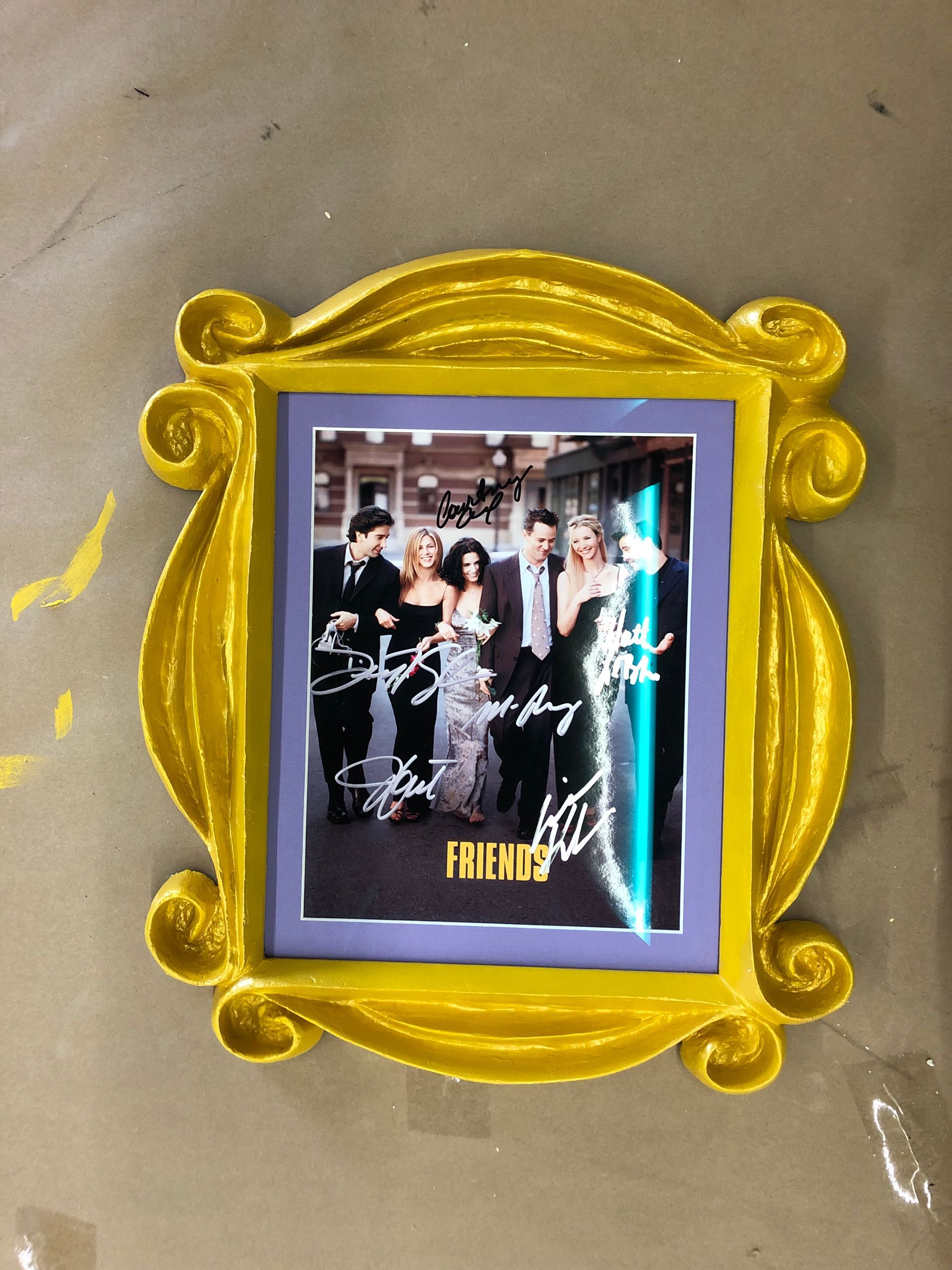 A yellow frame with a picture of friends on it