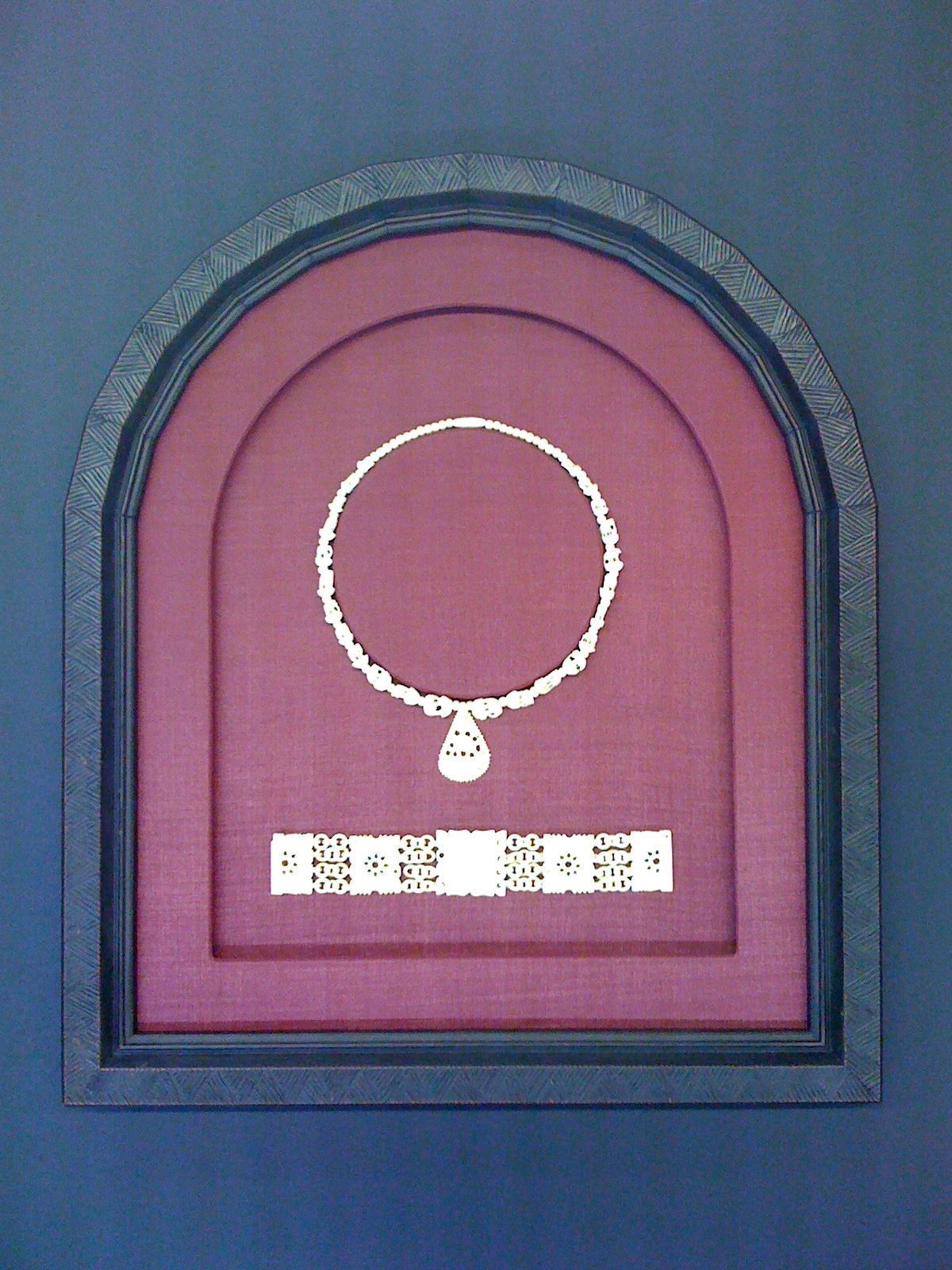 A picture of a necklace in a red frame