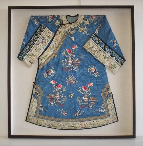 A blue and white dress is framed on a wall