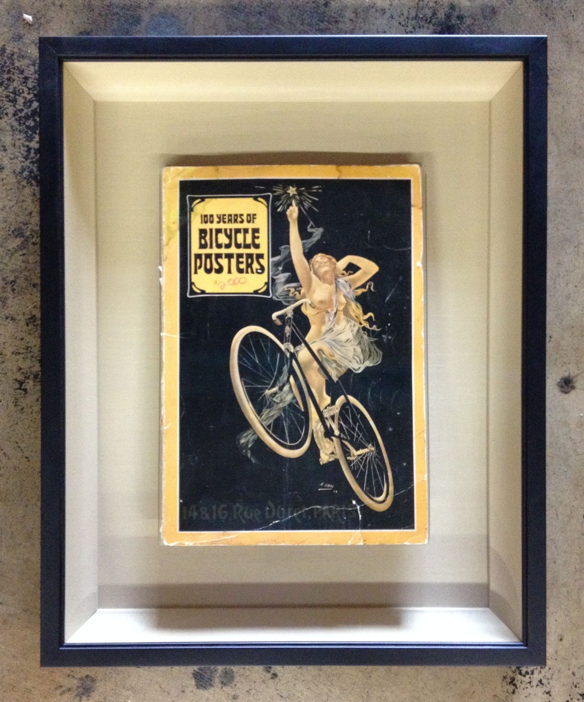 A framed picture of a woman on a bicycle titled 