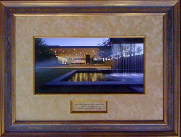 A framed picture of a house with a waterfall