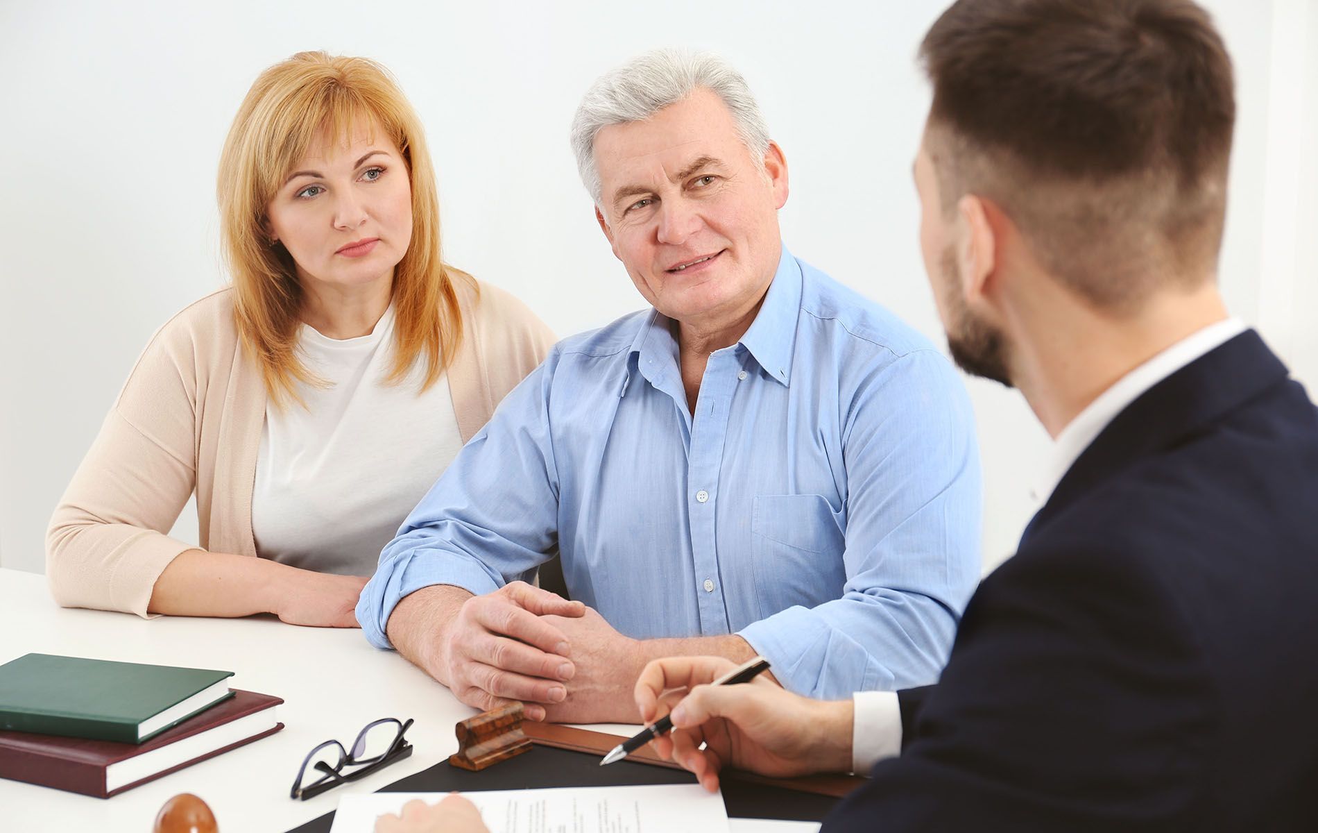 A couple listens to a lawyer at a table, discussing documents.