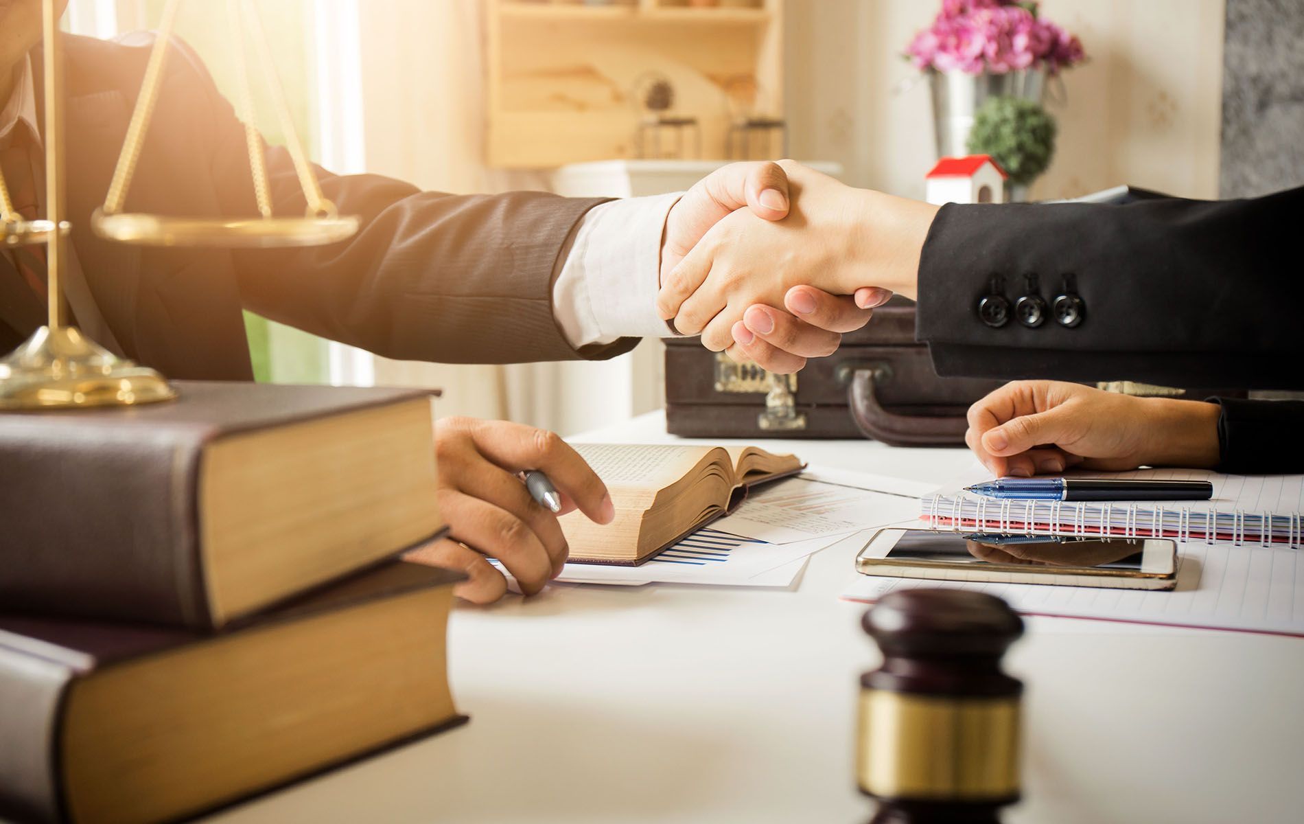 A lawyer is shaking hands with a client while sitting at a table.