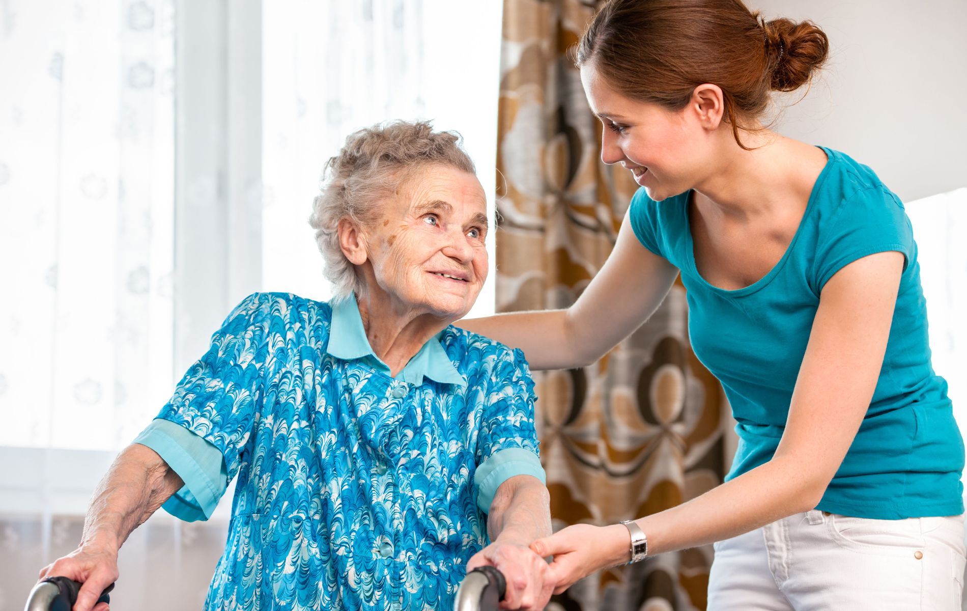 A woman is helping an elderly woman with a walker.